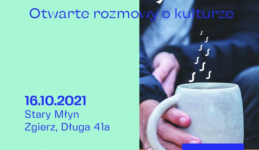 Zdjęcie promujące wydarzenie o nazwie „Kawa w Młynie” z tekstem „Otwarte rozmowy o kulturze”. Wydarzenie odbędzie się 16 października 2021 roku w Starym Młynie w Zgierzu. Zdjęcie przedstawia osobę trzymającą na drewnianym stole parujący kubek kawy.